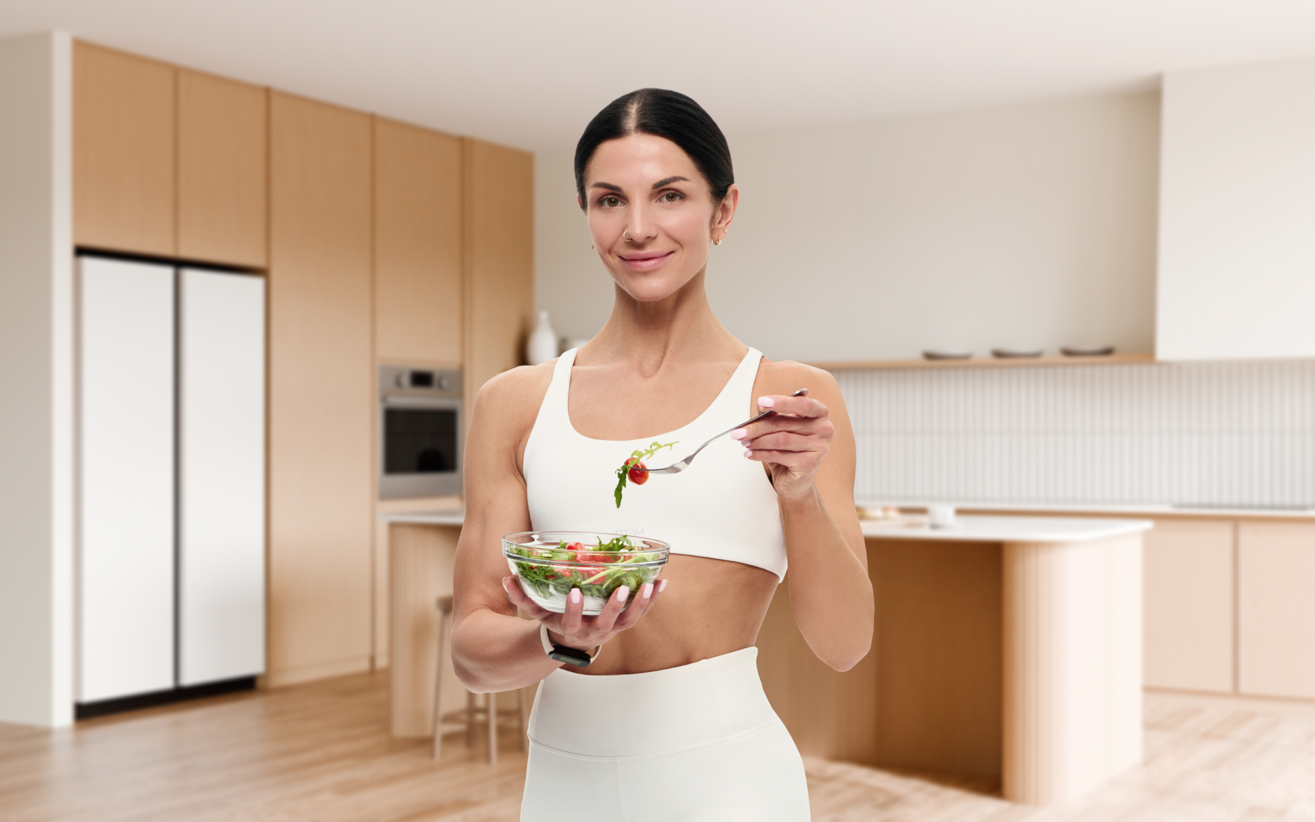 Best post workout meal shown as a woman in a modern kitchen enjoying a fresh salad after exercise, highlighting a simple healthy recovery meal.